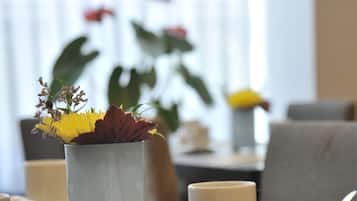 Una mesa de comedor con un florero, tazas blancas y un menú.