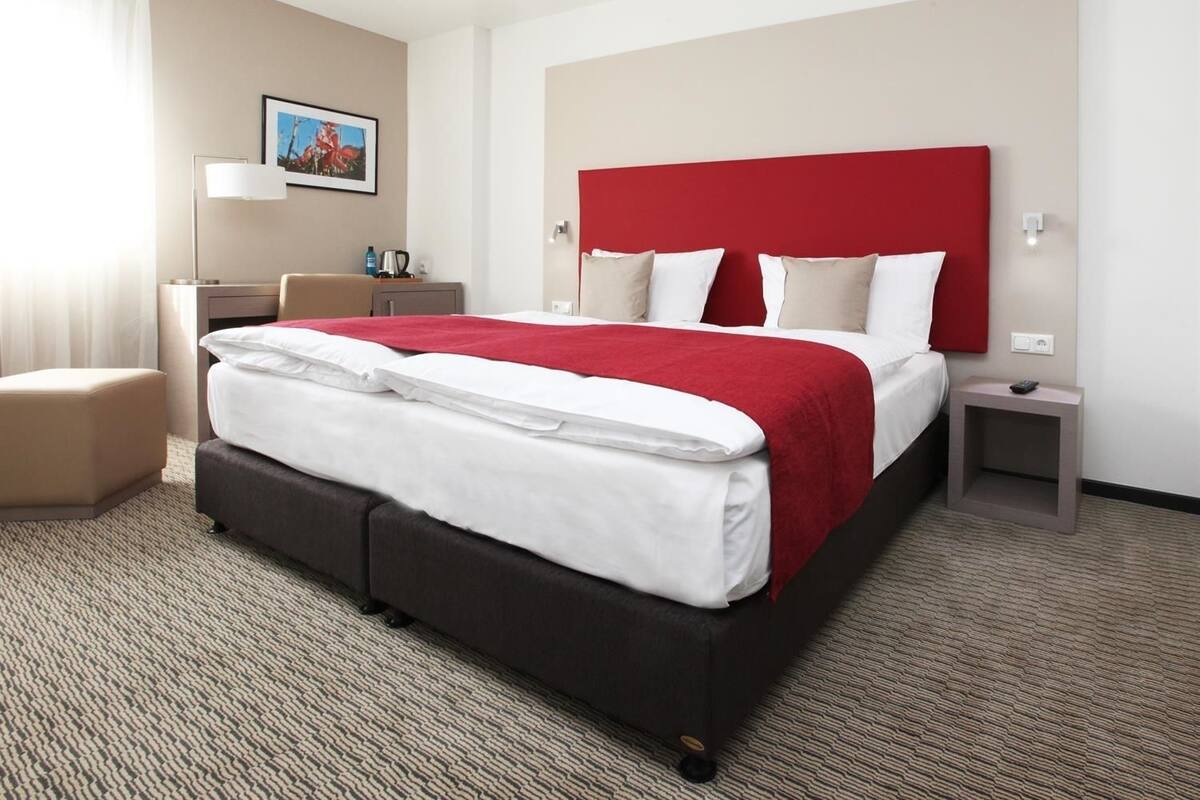 Une chambre d’hôtel avec un grand lit, un bureau, une chaise et une table de chevet.
