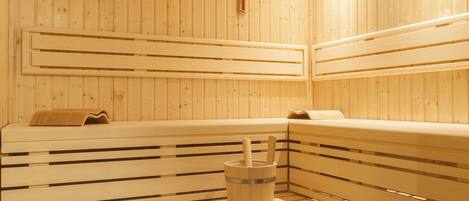 Una sauna de madera con bancos y un calentador de piedra.