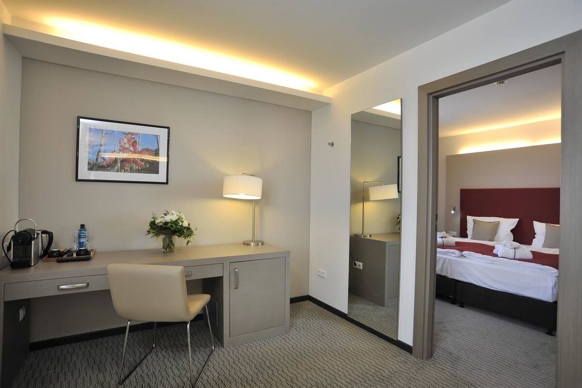 Une chambre d’hôtel équipée d’un bureau, d’une chaise, d’un lit et d’un grand miroir.
