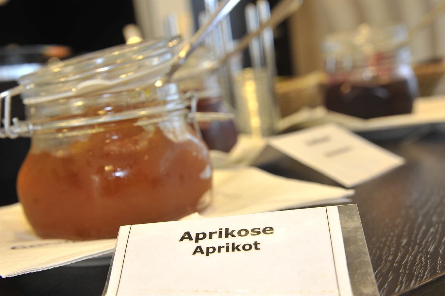 A jar of apricot jam with a label in front of it.