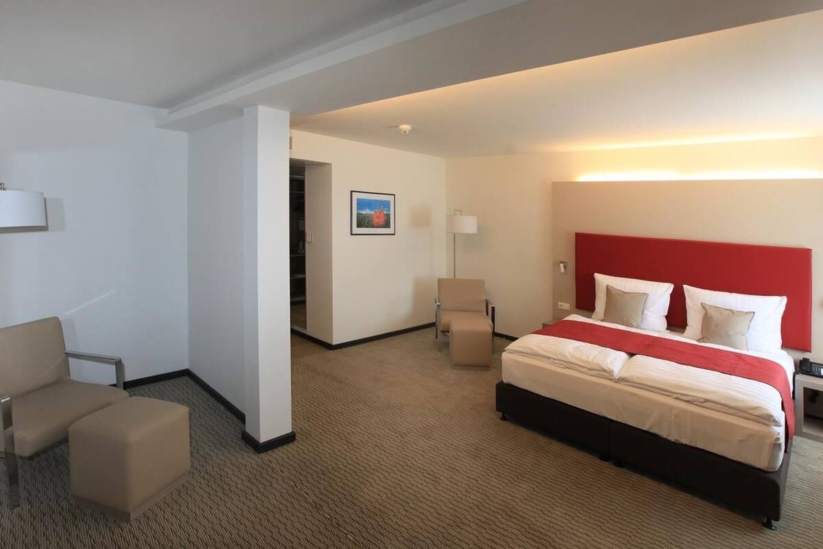 Une chambre d’hôtel avec un lit, une chaise, un bureau et une lampe.