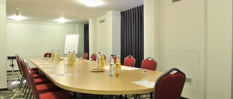 A conference room with a long table, red chairs, and water bottles.