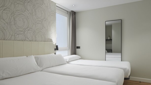 A hotel room with two beds, a large window, a mirror, and a patterned wall. - Hotel Arrizul Beach (San Sebastián)