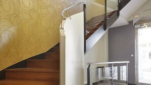 A wooden staircase with a glass railing, a patterned wall, and a tiled floor. - Hotel Arrizul Beach (San Sebastián)