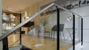 A modern interior with a glass staircase, wooden flooring, and contemporary furniture. - Hotel Arrizul Beach (San Sebastián)