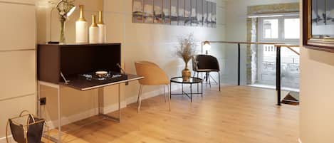 A modern living room with a wooden floor, a black sofa, a round table, and a decorative vase.