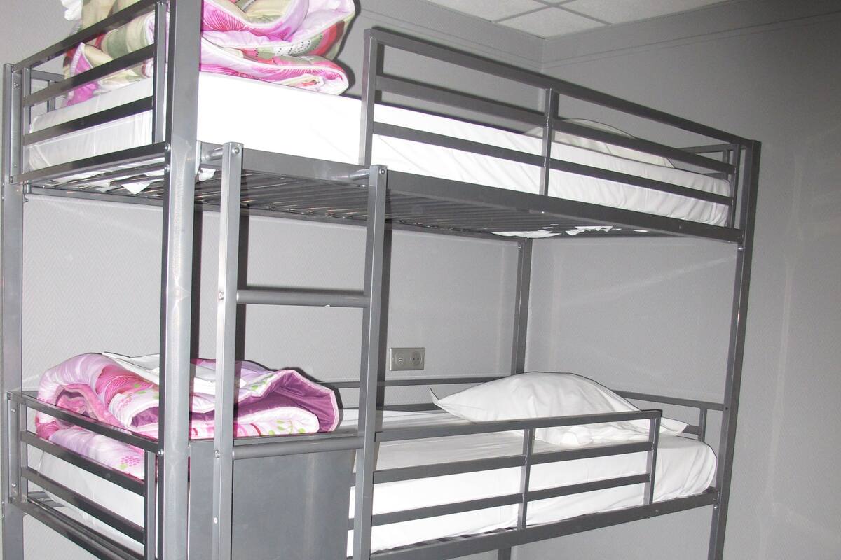 A bunk bed with multiple levels, each with a mattress and pillows.