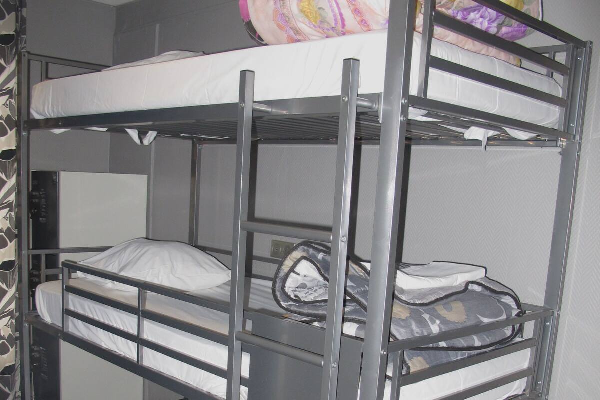A bunk bed with three levels, each with a mattress and pillows.