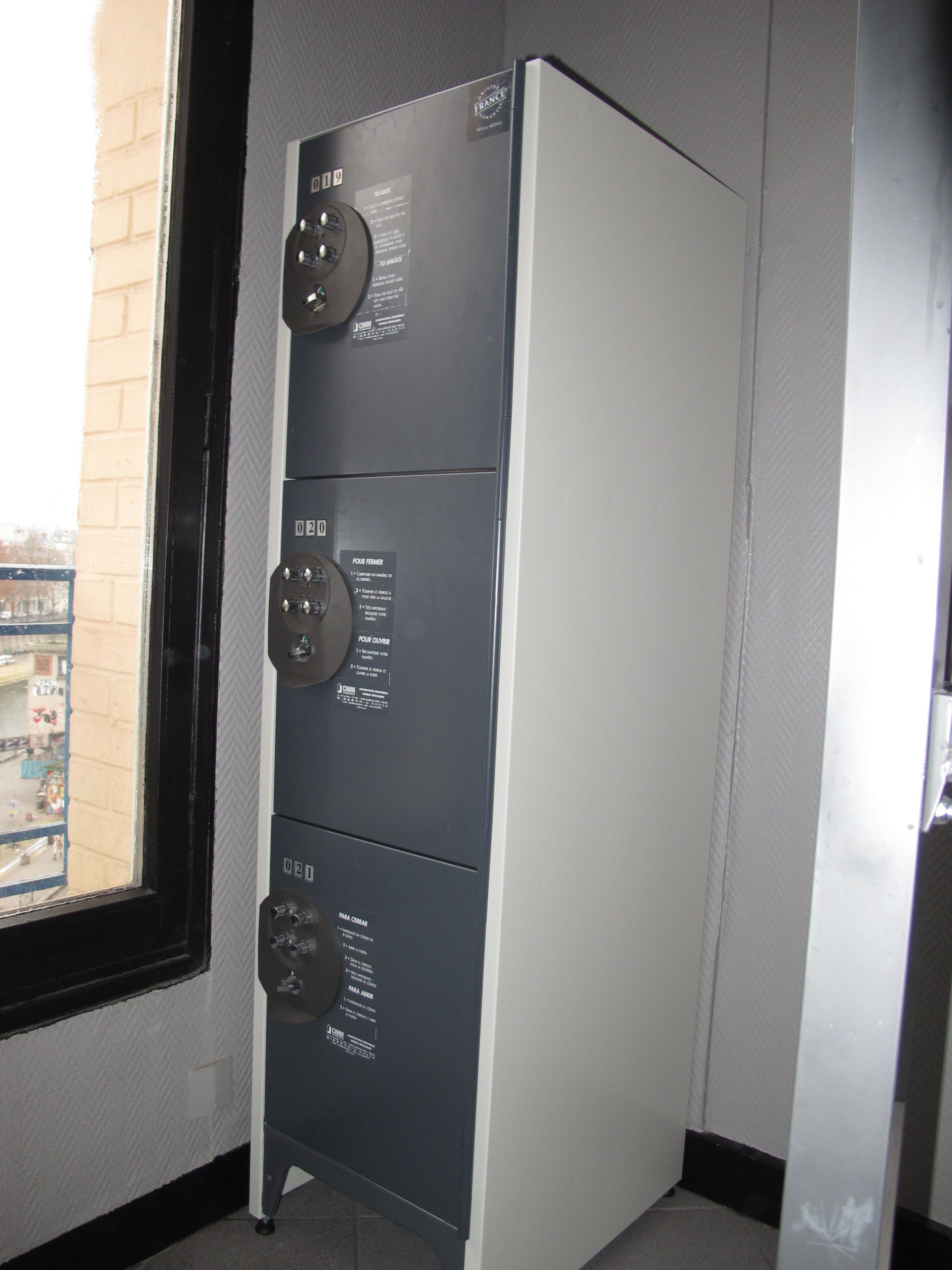 Un cuarto de servicio metálico con ventana, puerta y panel de control montado en la pared con etiquetas.