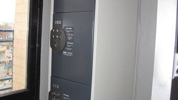 Un cuarto de servicio metálico con ventana, puerta y panel de control montado en la pared con etiquetas.