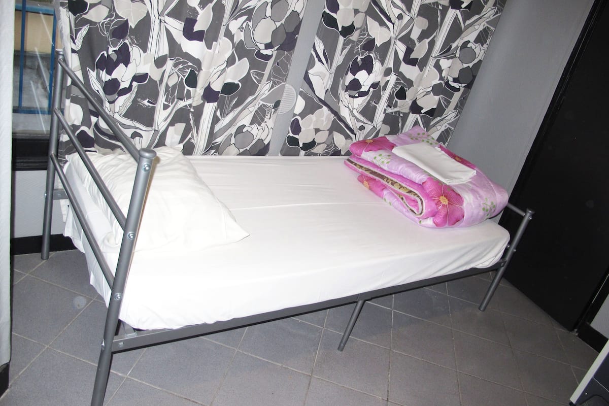 A single bed with a metal frame, a white mattress, and a floral-patterned headboard.