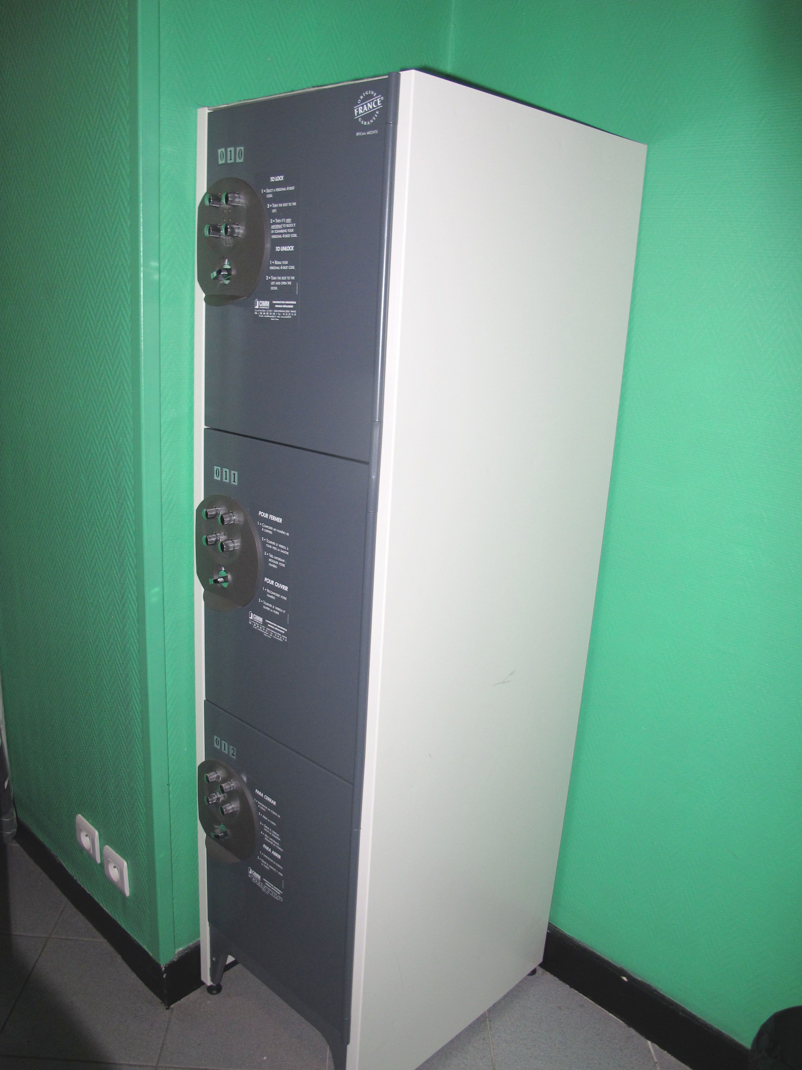 Een kamer met een groene wand en een witte kast met verschillende vakken.