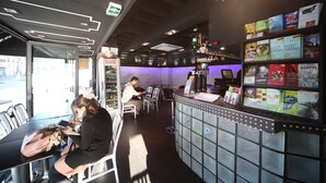 Una zona de bar con asientos, una barra con libros y un refrigerador de Coca-Cola.