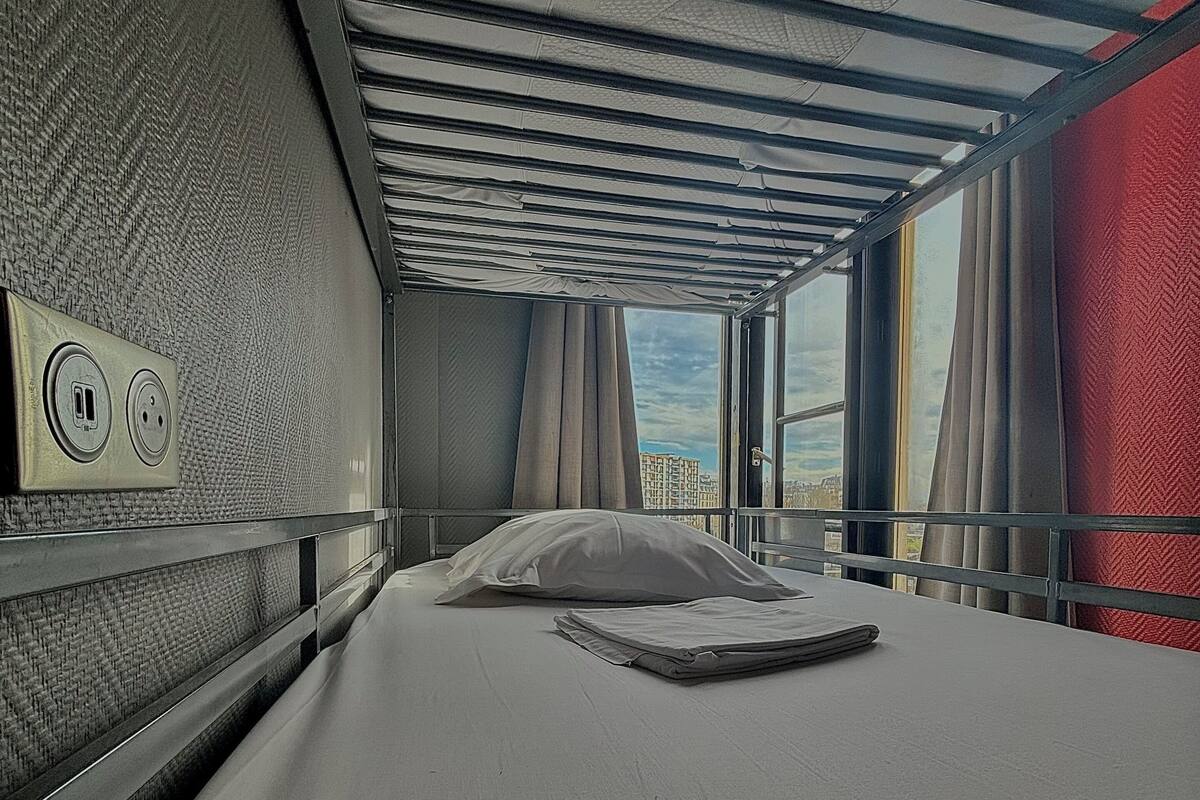 A train car with a bed, a window, and a power outlet.