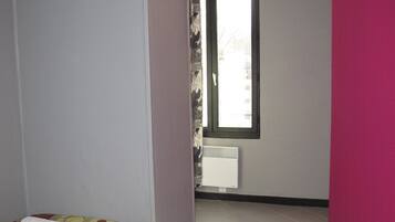 Una habitación de hotel con una cama, una ventana y una puerta que da a otra habitación.