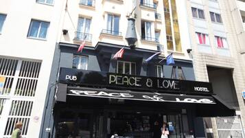 A hostel named "Peace & Love" with a black awning, outdoor seating, and a flag.