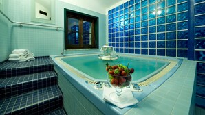 Un baño con bañera, una ventana y un frutero en el borde de la bañera.