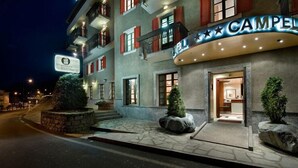 Un hotel con un letrero de marquesina curvo, escalones de piedra y plantas en macetas.