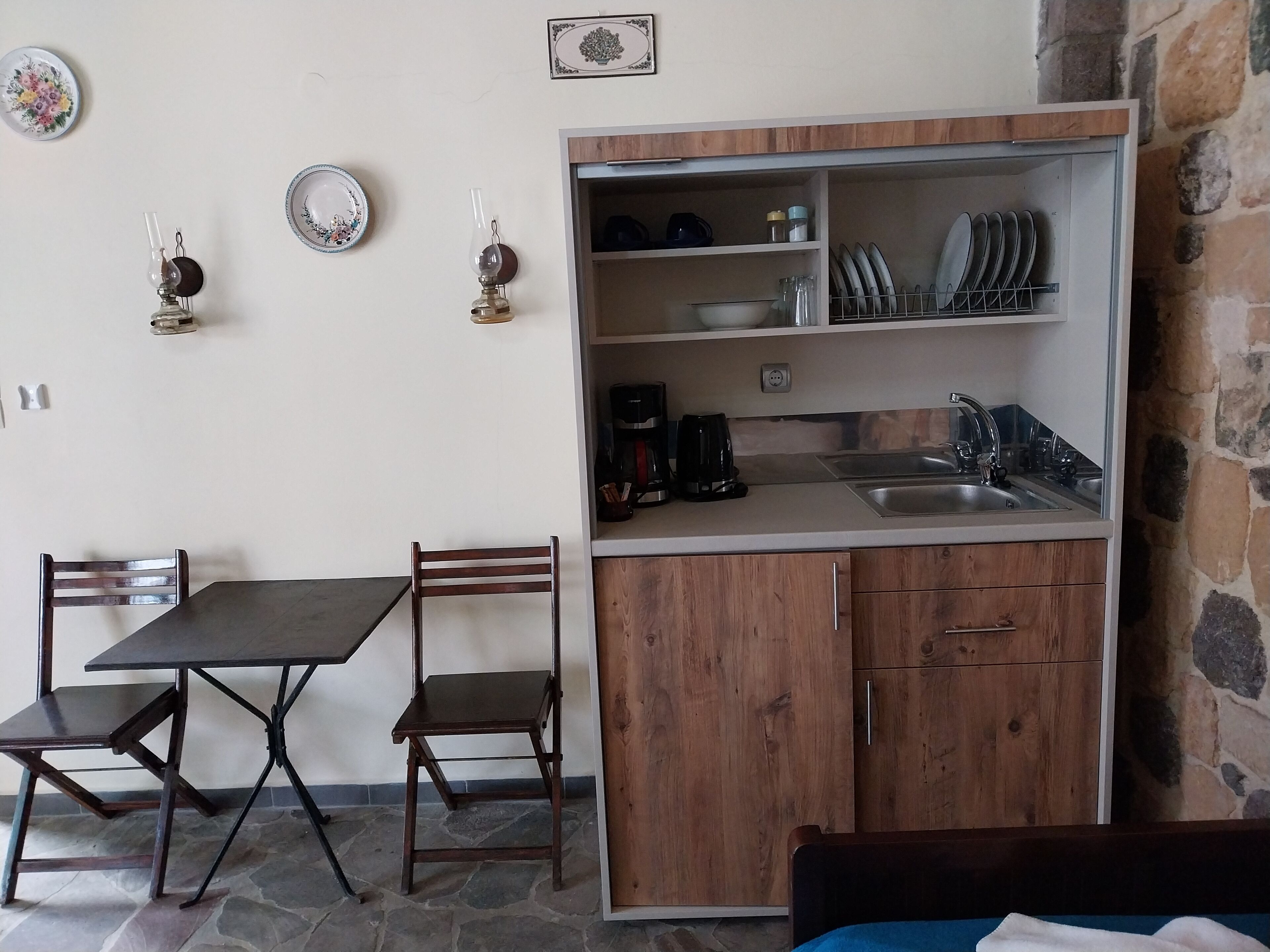A compact kitchen with a dining table and chairs, a coffee maker, and a sink.