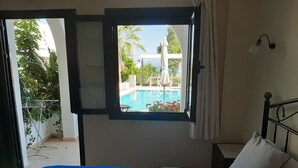 Un dormitorio con una cama y un ventanal con vistas a una piscina y zona exterior.