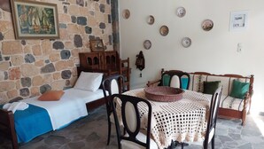 Una habitación acogedora con cama, un aparador de madera, una mesa de comedor con sillas y una pared de piedra con un cuadro.