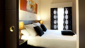A hotel room with a bed, pillows, a nightstand, a lamp, and a painting on the wall. - THC Tirso Molina Hostel (Madrid)