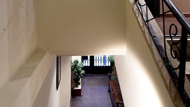 A staircase with a black and white photograph of a historic building, a metal railing, and a door. - THC Tirso Molina Hostel (Madrid)