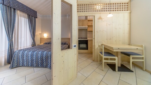 A compact room with a bed, a small kitchenette, and a dining area.