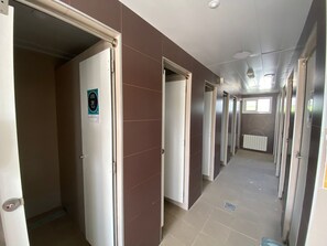 A corridor with doors leading to individual rooms, a sign indicating a smoking area, and a radiator on the wall. - Camping Armanello (Benidorm)
