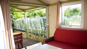Une pièce avec un canapé rouge, une table en bois et une fenêtre donnant sur un paysage verdoyant.