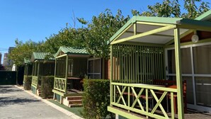 Une rangée de maisons mobiles vertes, toutes dotées d’une véranda attenante et d’un petit escalier menant à l’entrée.