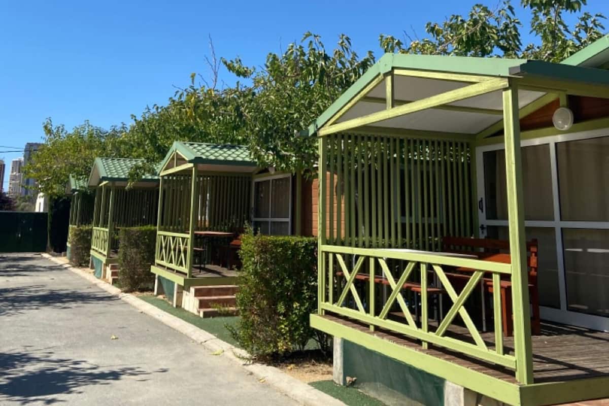 Una fila de casas móviles verdes con porches anexos, cada una con un pequeño tramo de escaleras que conduce a la entrada.
