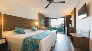 Une chambre d’hôtel avec un grand lit, un bureau, un ventilateur de plafond et une vue sur l’extérieur.