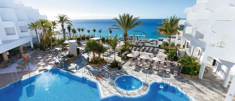 Una piscina al aire libre, sombrillas, sillones reclinables de piscina