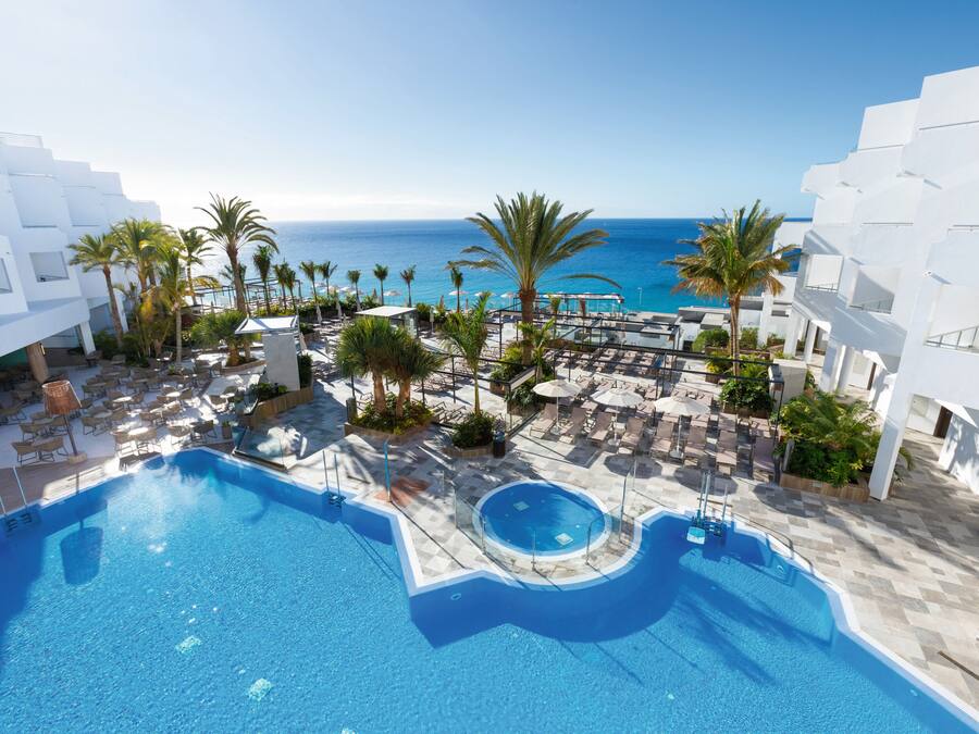 Una piscina al aire libre, sombrillas, tumbonas