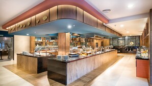 A modern buffet with a central island, wooden paneling, and a variety of food displays.