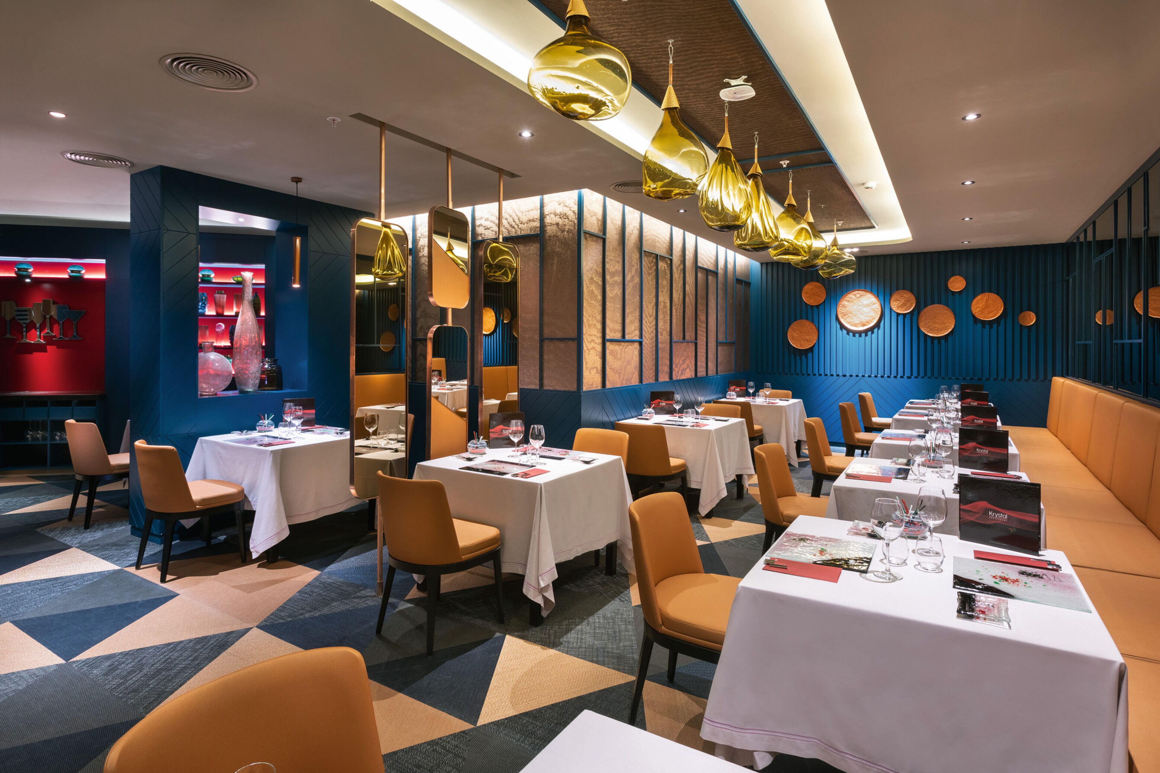 Un restaurant avec des tables dressées pour le service, un bar et un coin salon avec un canapé.