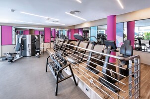 Un gimnasio moderno con máquinas de cardio, equipo de levantamiento de pesas y espejos.