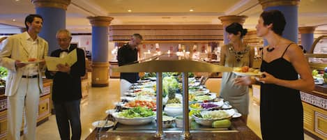 A buffet setup with various food items and waitstaff.
