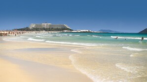 A beach with a large hotel in the background. - Hotel Riu Palace Tres Islas (La Oliva)