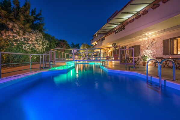 A swimming pool with a view of a building with outdoor seating and a covered area.