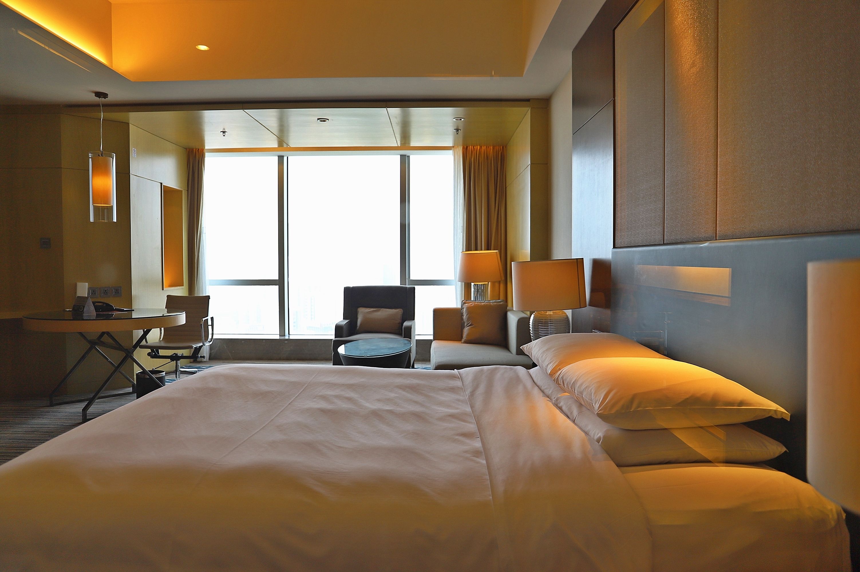 A hotel room with a large bed, a desk, a chair, and a sofa.