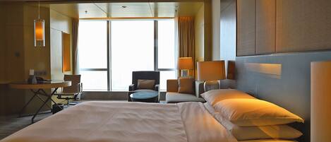 A hotel room with a large bed, a desk, a chair, and a sofa.