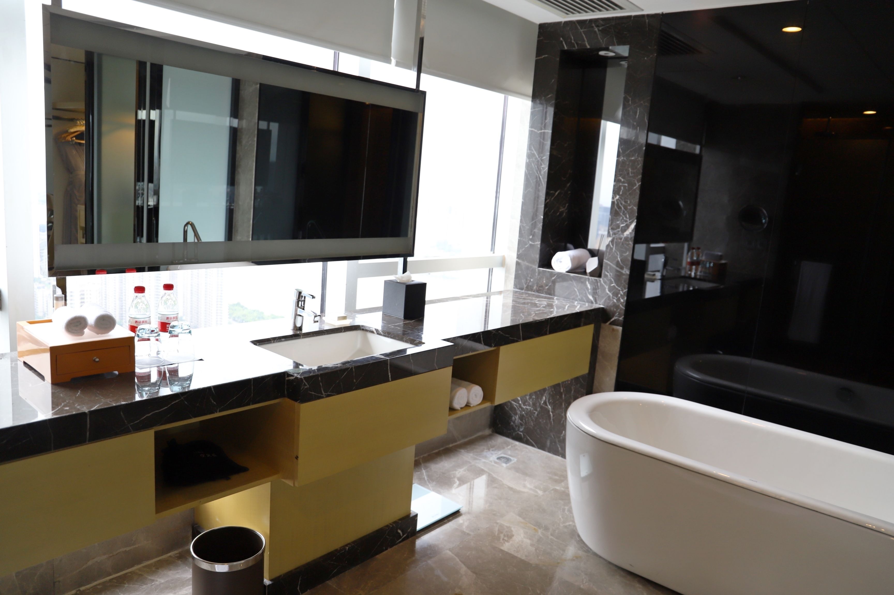 A modern bathroom with a large mirror, a bathtub, and a vanity with a sink.