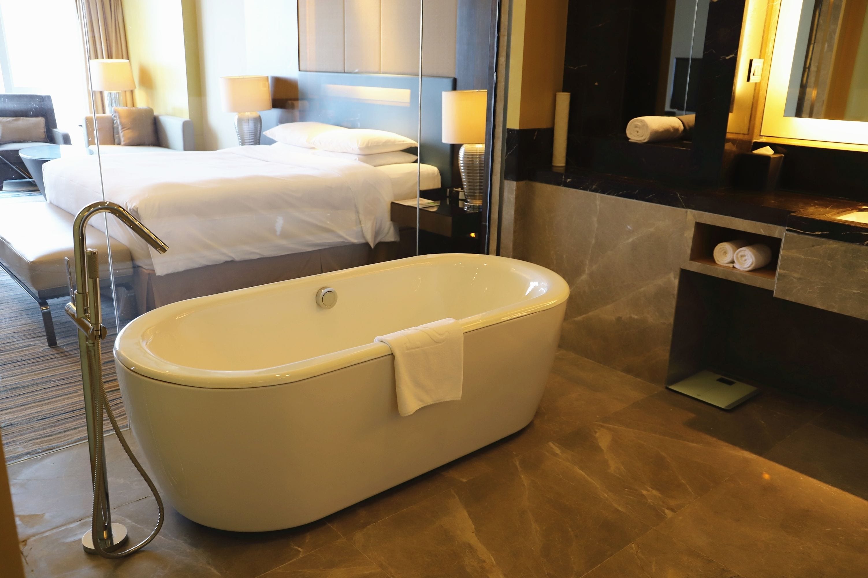 Ein modernes Badezimmer mit einer freistehenden Badewanne, einem großen Spiegel und einem Waschtisch mit Handtuchhalter.