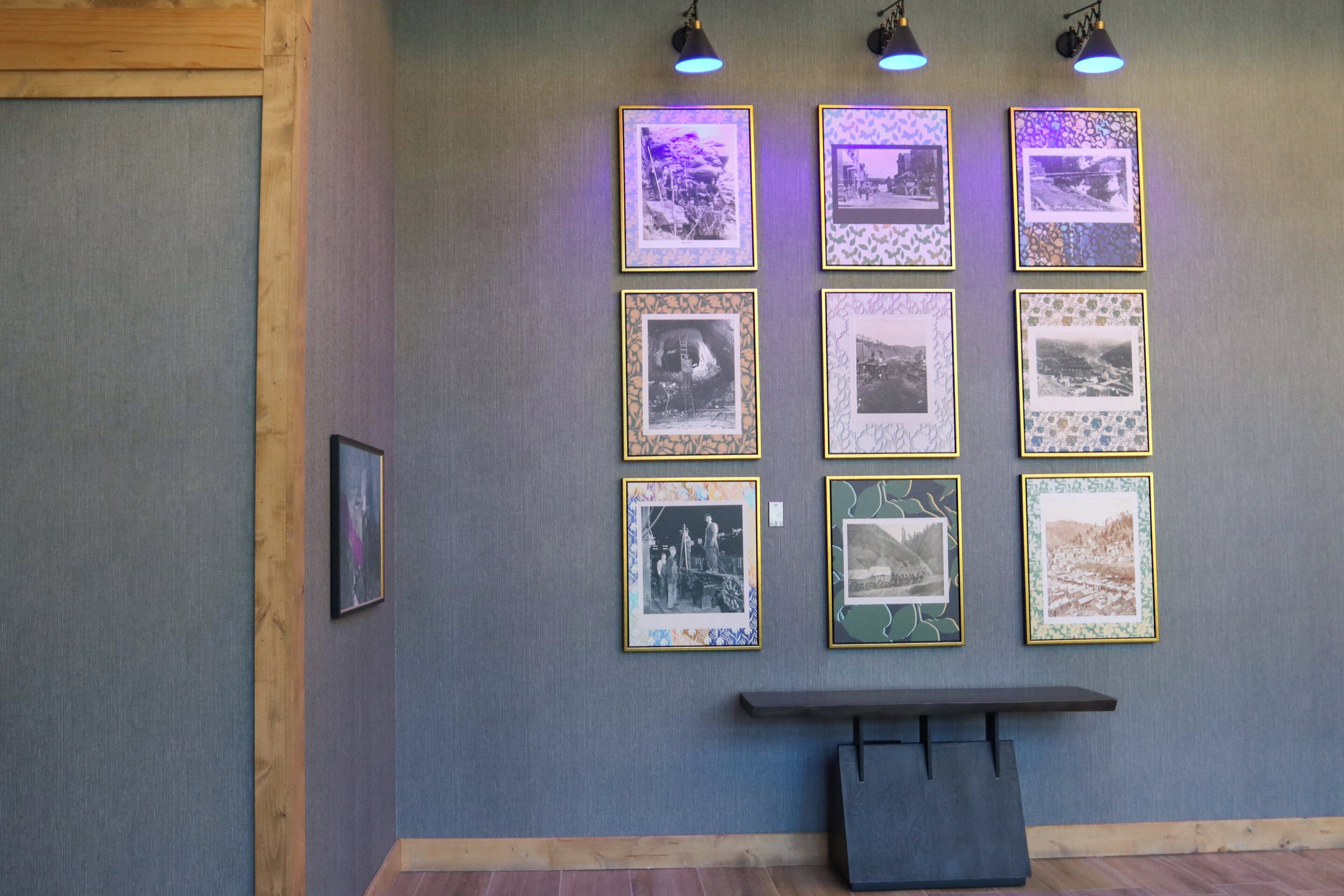 A wall with framed photographs and a bench.