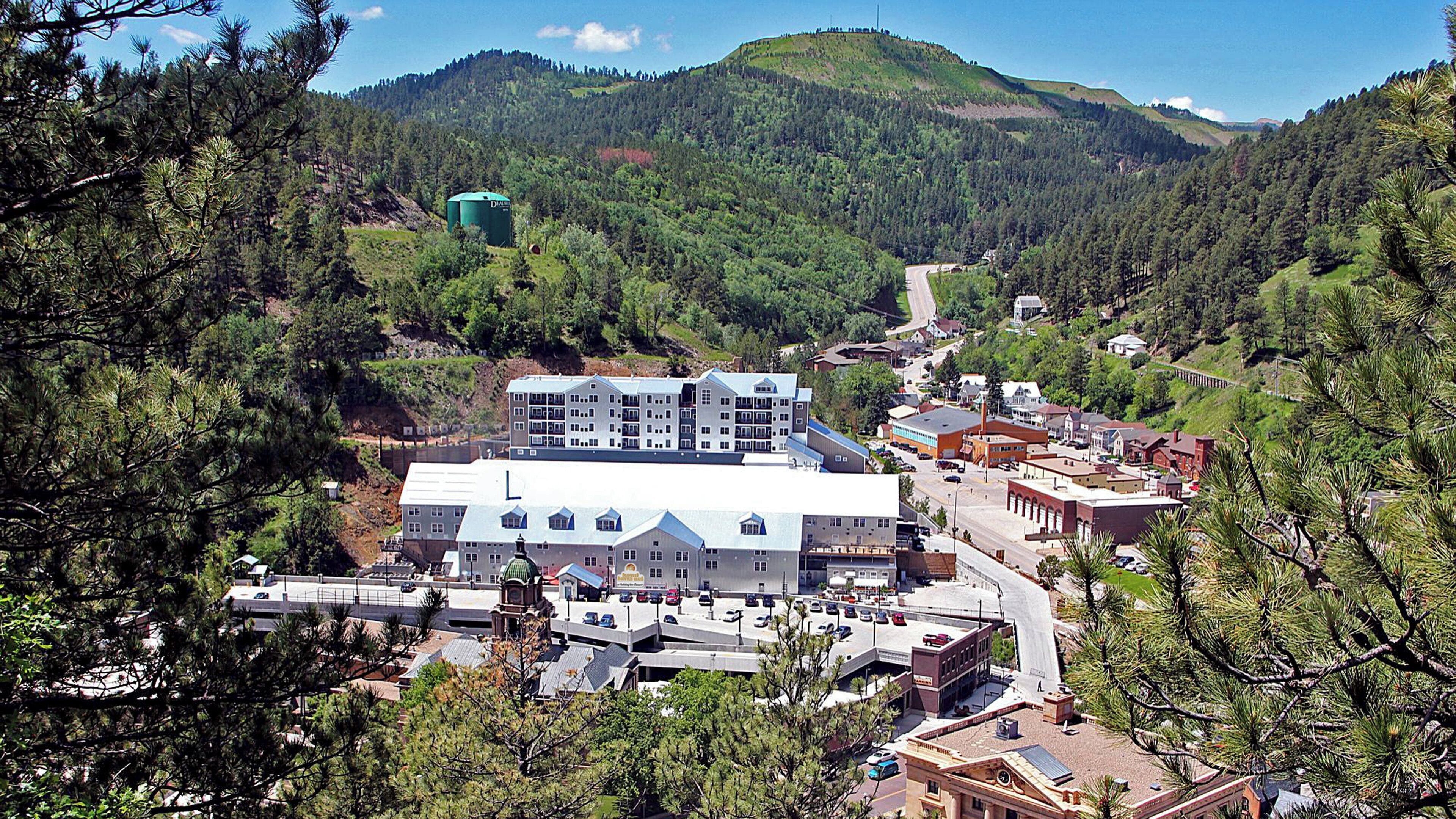 Un pueblo con un edificio blanco destacado y una cúpula, rodeado de edificios más pequeños y un paisaje montañoso.