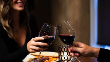 Dos personas brindando con copas de vino en una mesa con un candelabro y un plato de comida.