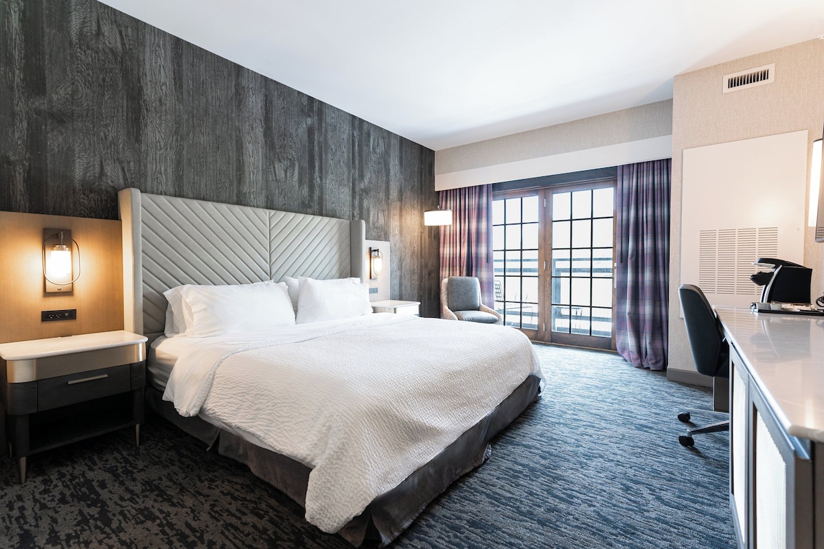 Quarto de hotel moderno com uma cama grande, uma escrivaninha e uma cadeira.